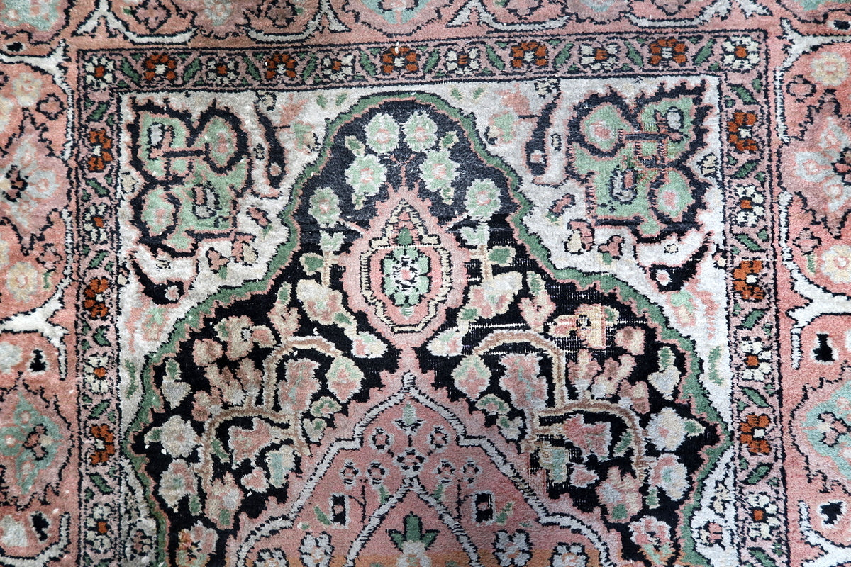 A side angle of the rug’s silk sheen and detailed pink floral border
