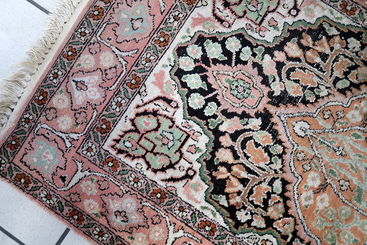 A collector holding the 2.5' x 4.3' vintage Persian silk rug, showing its size
