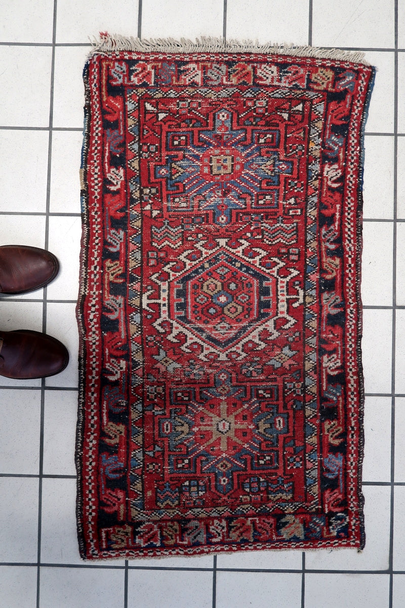 Persian Karajeh tribal rug displayed on a wooden floor, showcasing its traditional design
