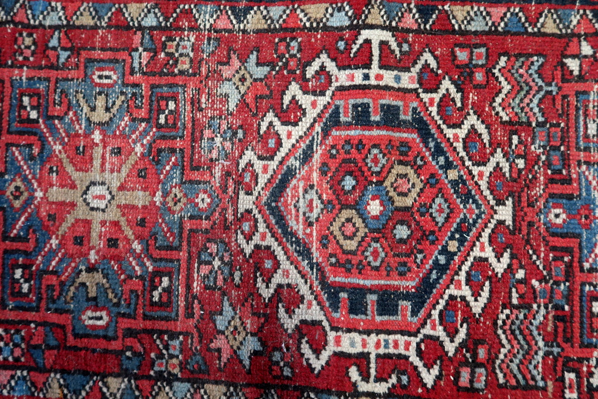 Vintage Persian rug with a decorative multi-toned border and intricate tribal motifs
