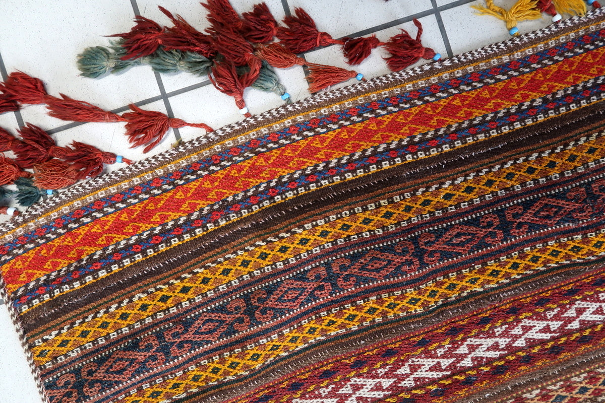 Flat-woven Moroccan Kilim rug featuring deep reds, earthy browns, and golden yellows
