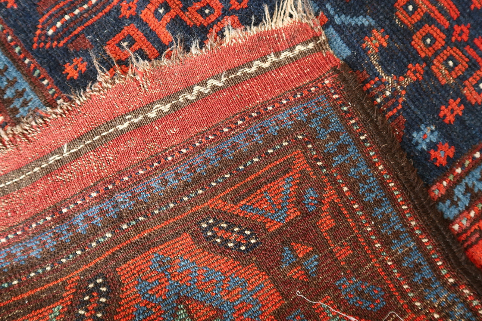 Side angle view of a handmade Baluch wool rug, showing texture
