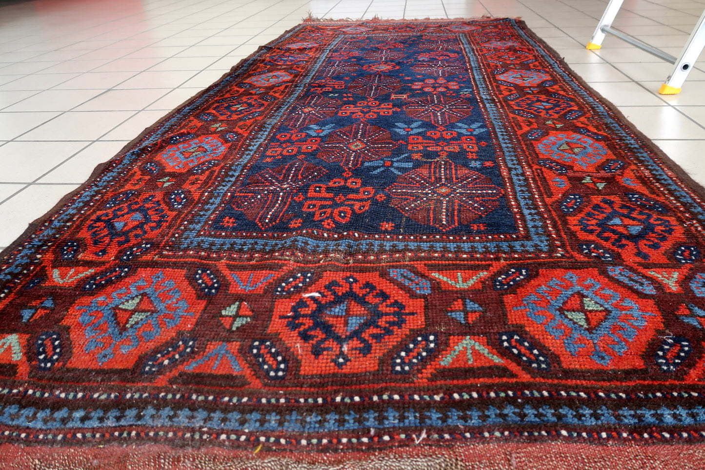 Antique Afghan Baluch rug with warm reds and deep blues
