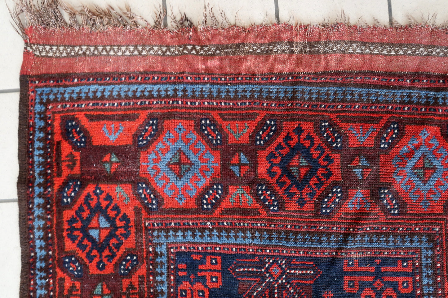 Close-up of intricate geometric patterns on 1880s Afghan wool rug
