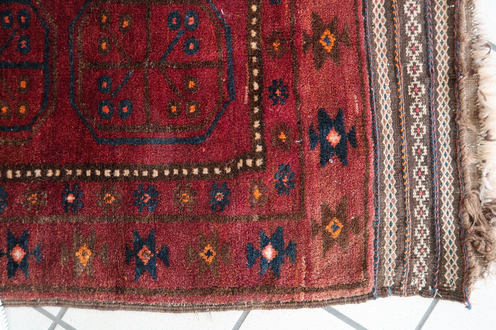 Afghan Baluch rug with symmetrical medallion motifs and earthy tones
