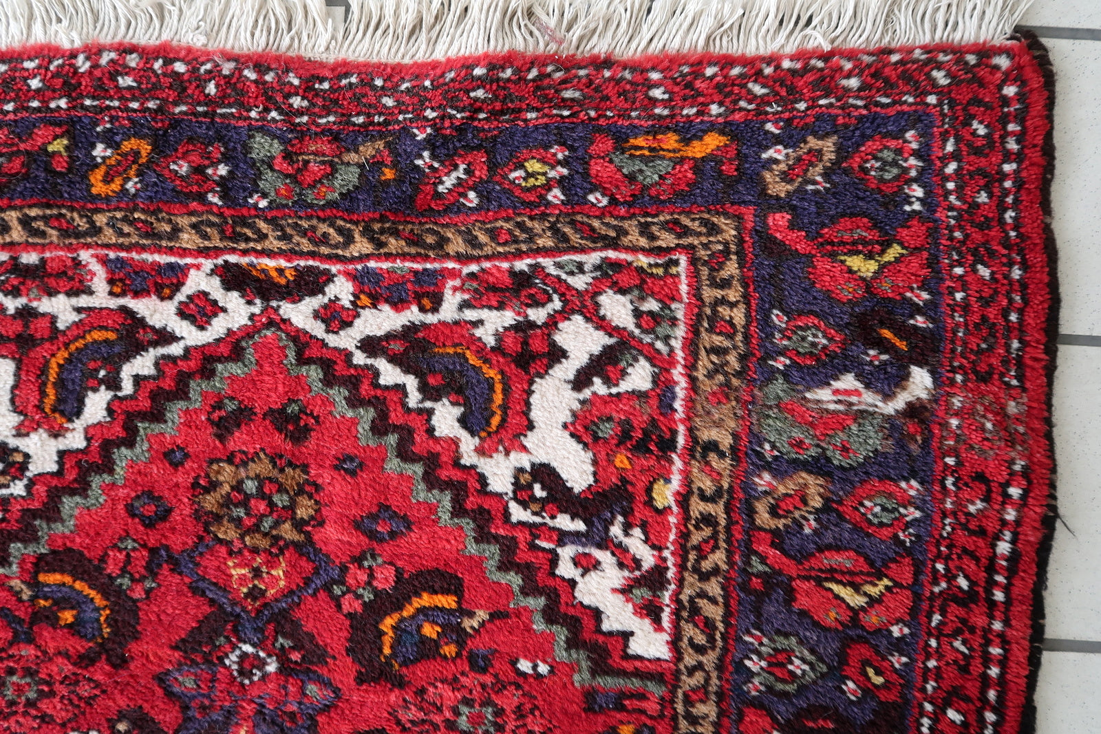 Red and navy Persian rug with floral and geometric patterns
