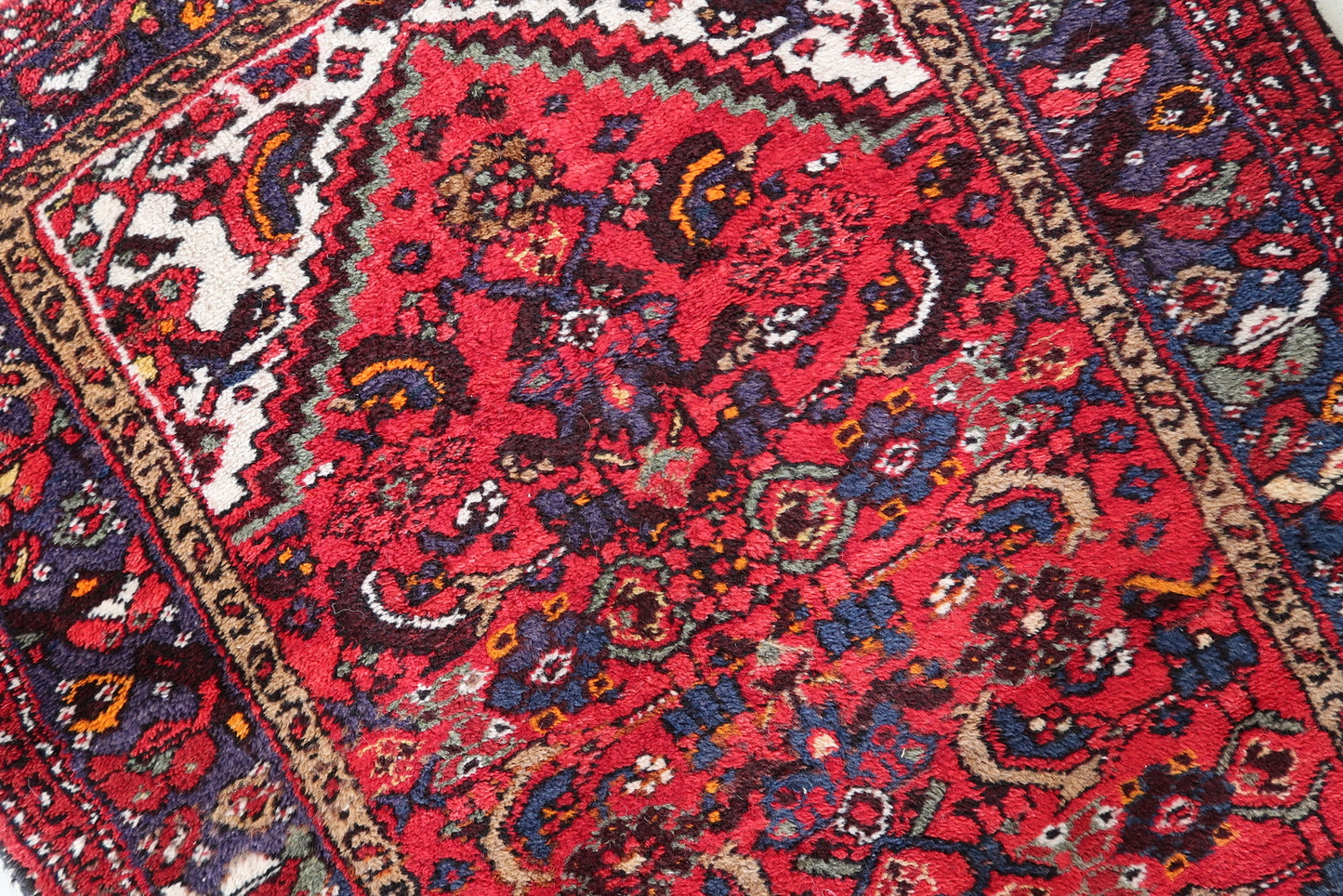 Close-up of vintage Persian rug showing delicate vines and blossoms
