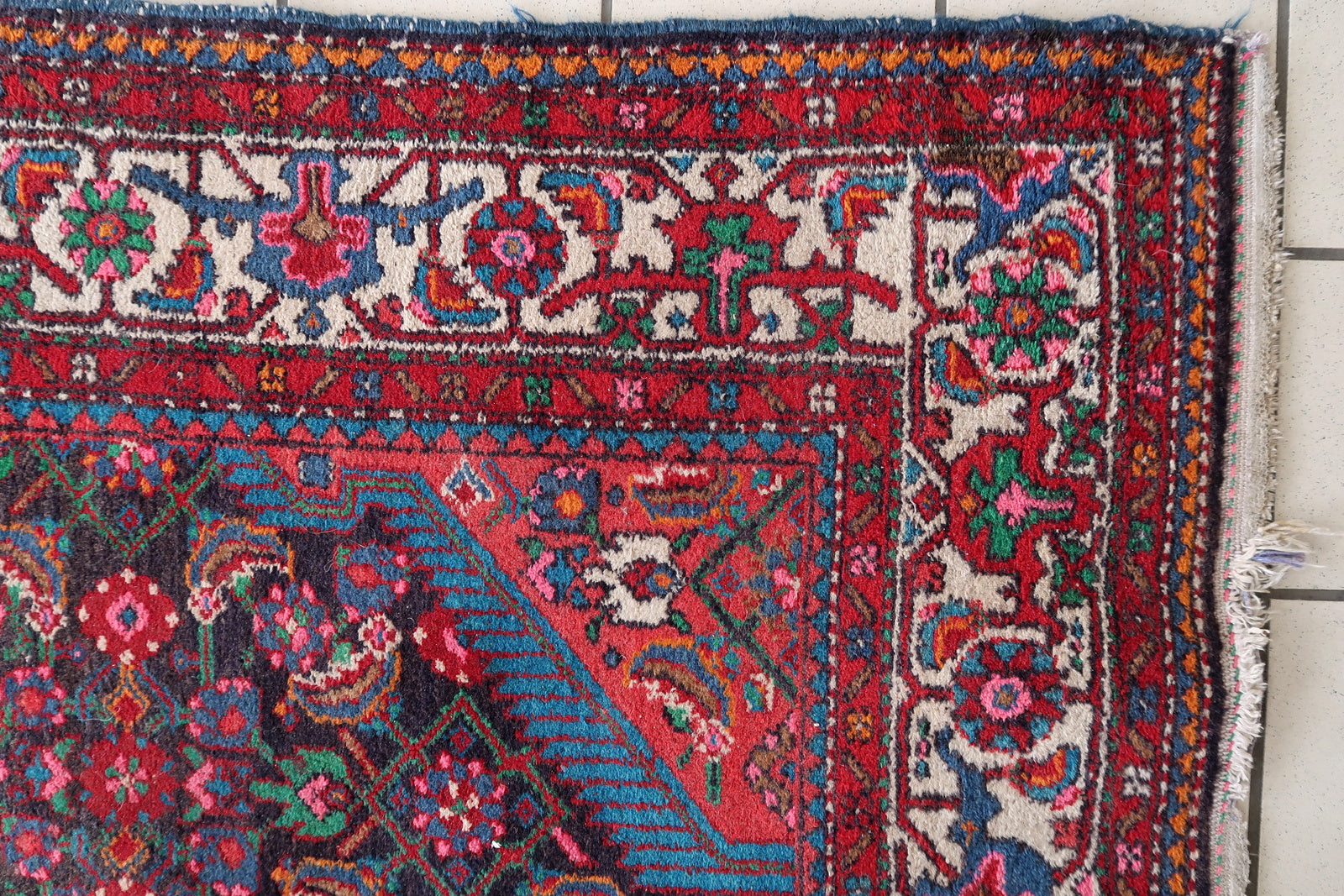 Red and navy Persian rug with central medallion and floral patterns
