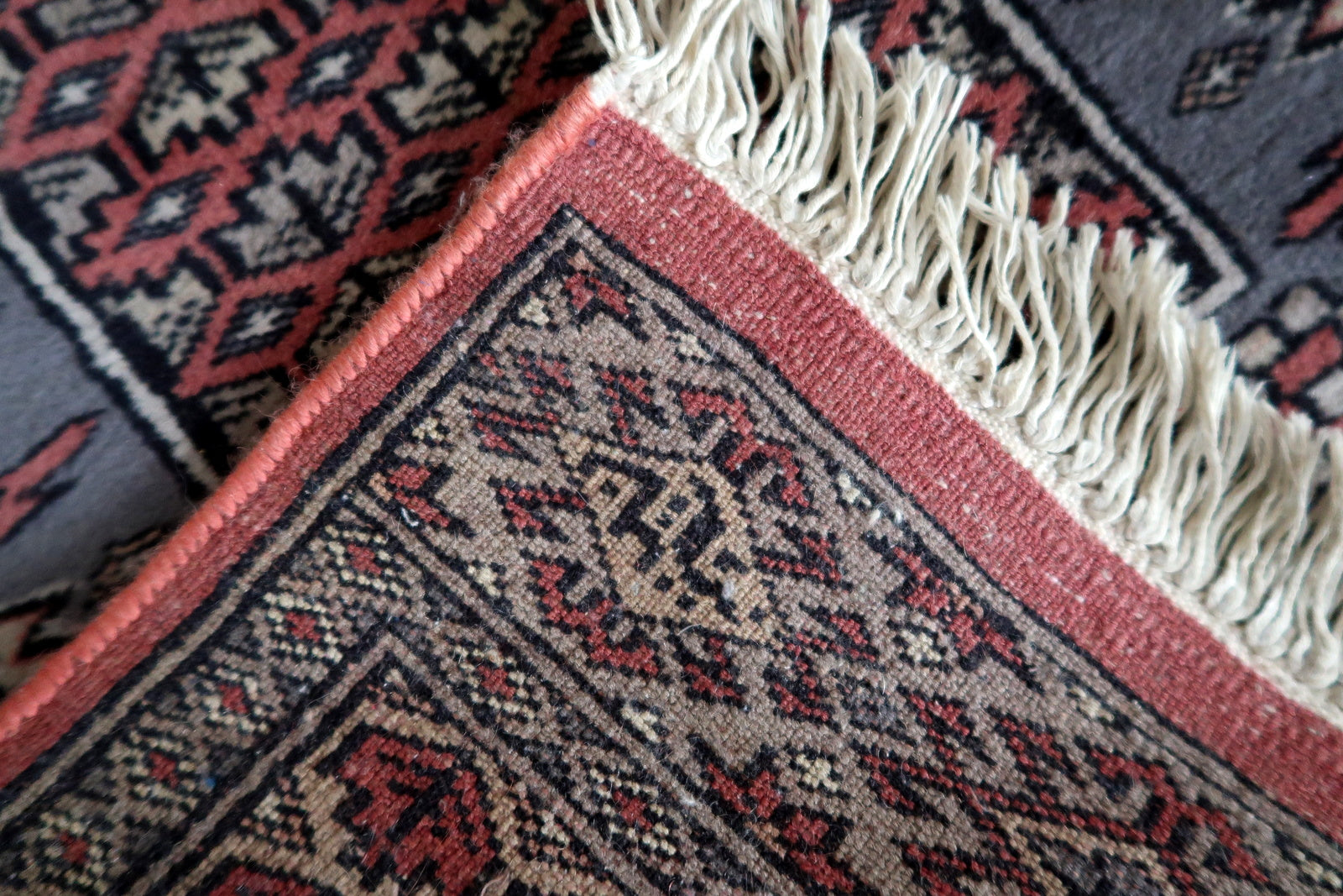 Vintage Bukhara carpet with fringed edges
