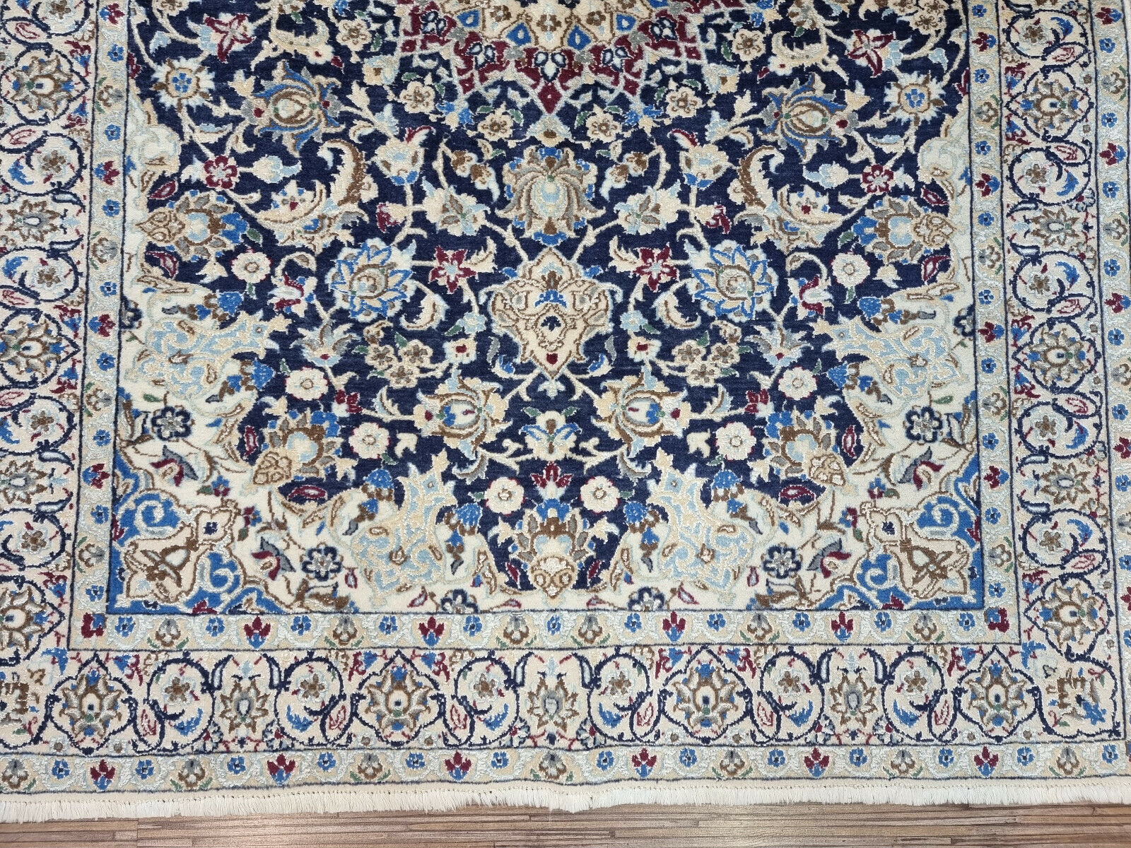 Vintage Persian-style Nain rug displayed on hardwood floor
