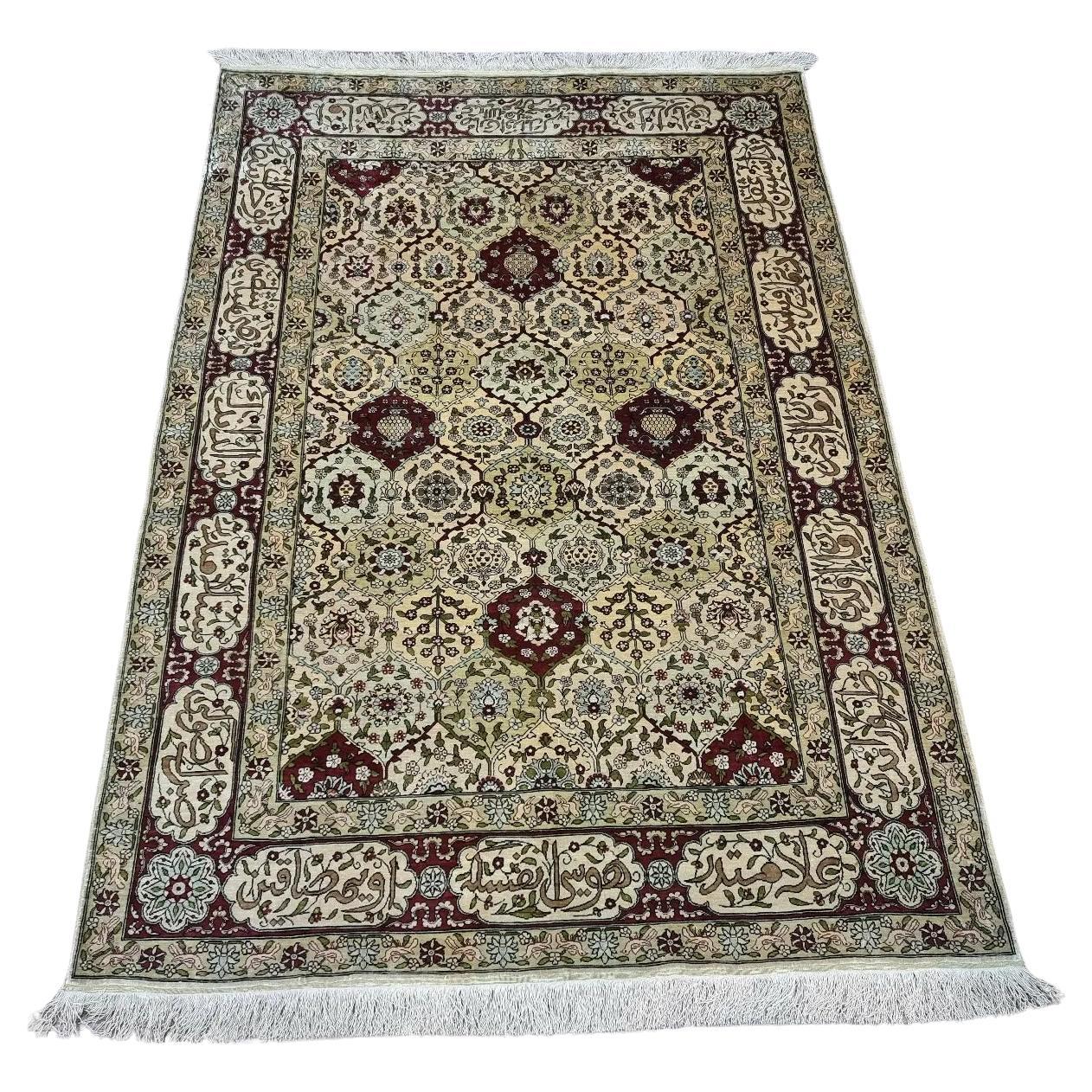 Handmade vintage Turkish Hereke silk rug with floral and calligraphic motifs in gold and burgundy tones
