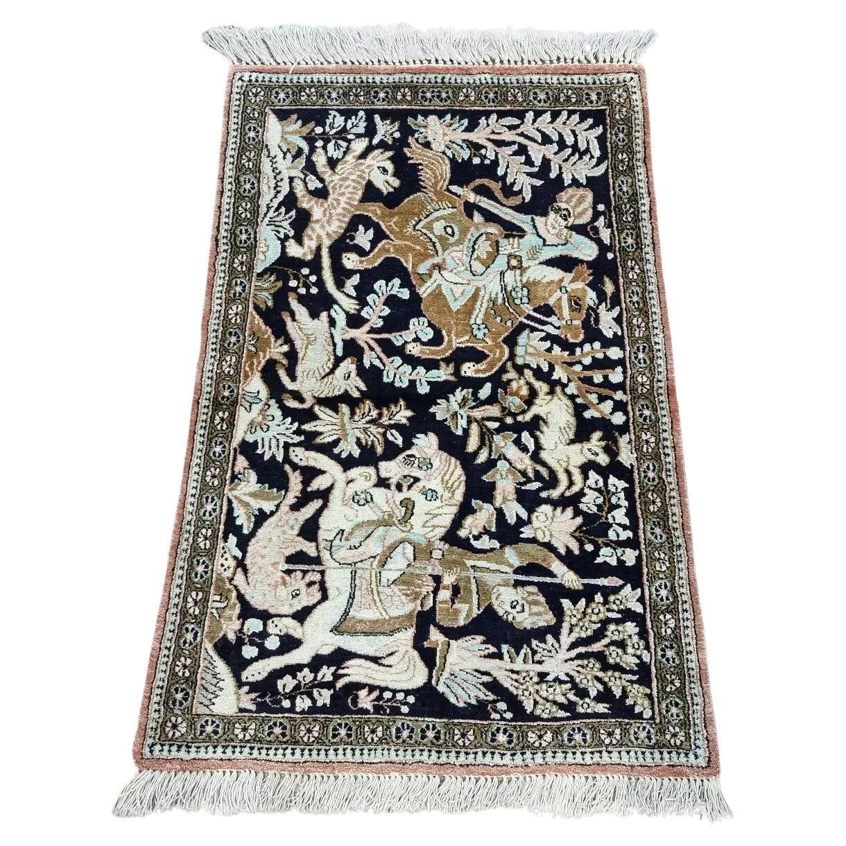 Persian-style Qum silk rug with hunting scenes, featuring mounted riders and exotic animals on a navy-blue background
