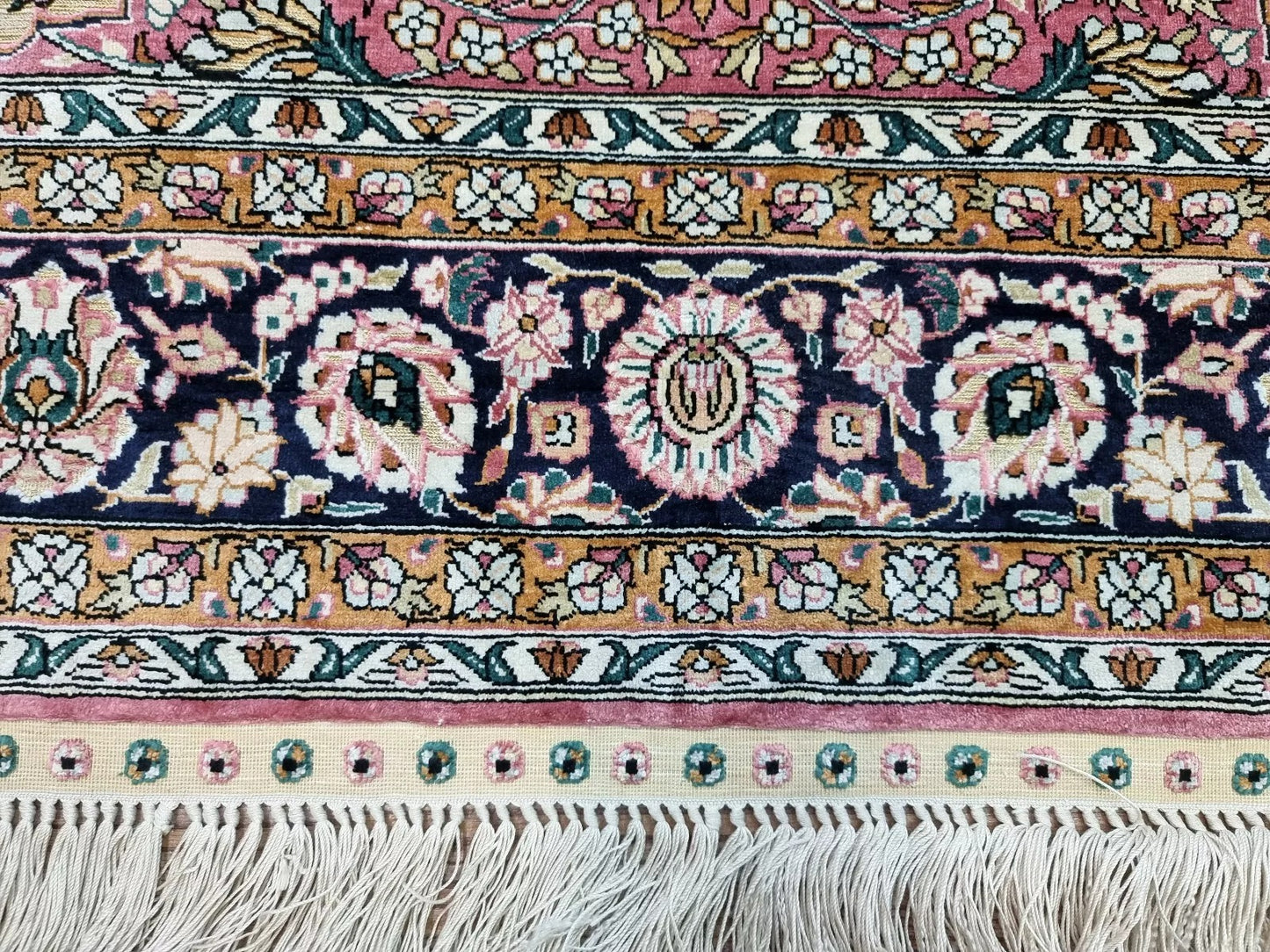 Close-up of intricate hand-knotted silk pattern on Chinese Qum rug.
