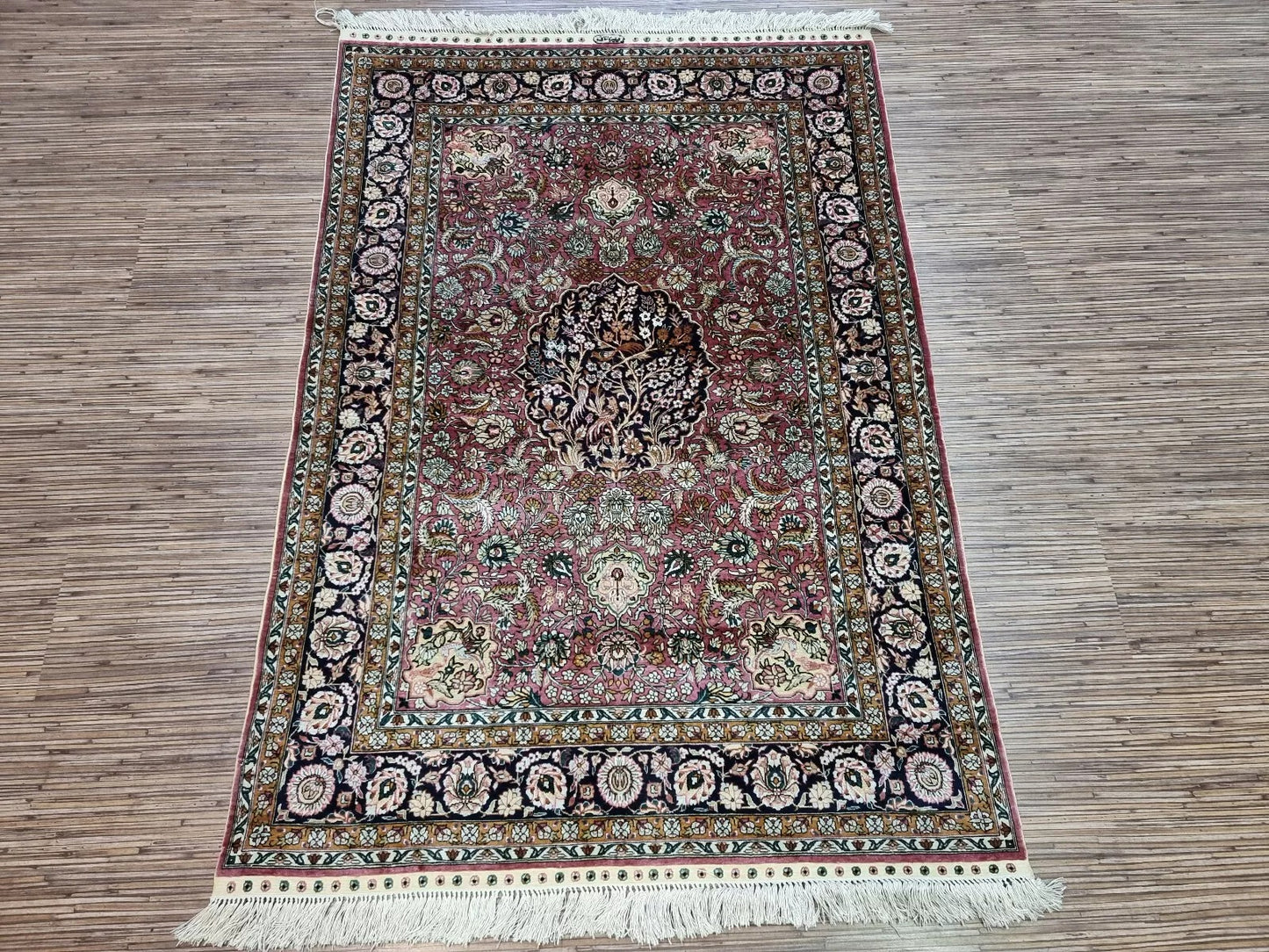 Vintage Hereke-inspired rug displayed on hardwood flooring.
