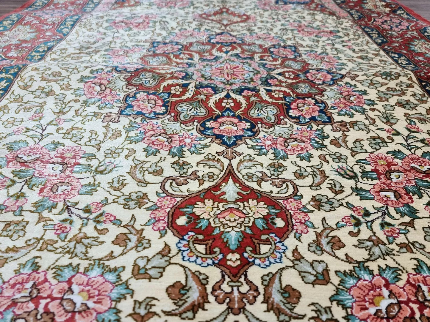 Close-up of intricate hand-knotted details on a Qom silk rug.
