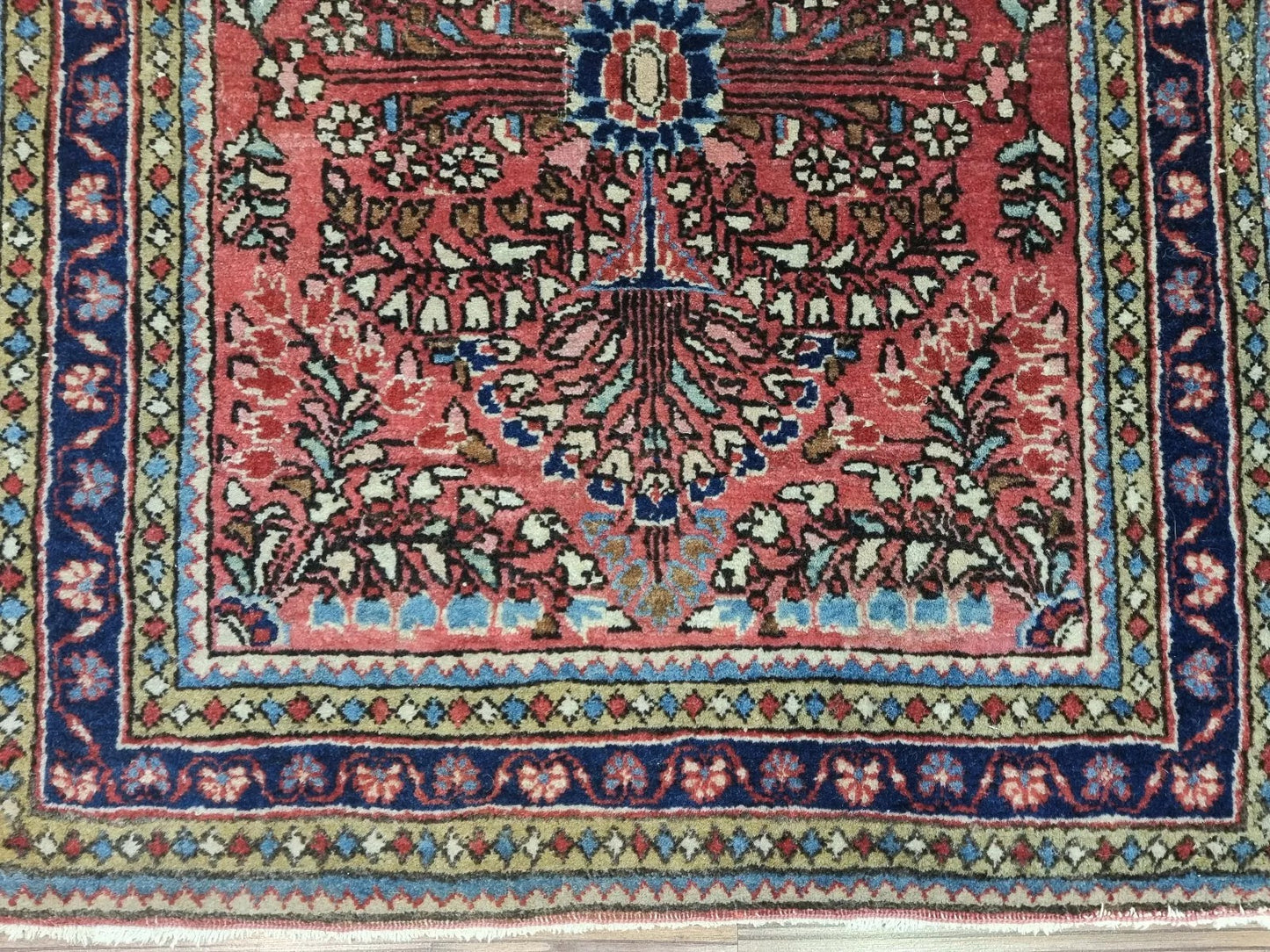 Close-up of intricate floral medallion details on an early 1900s Sarouk rug
