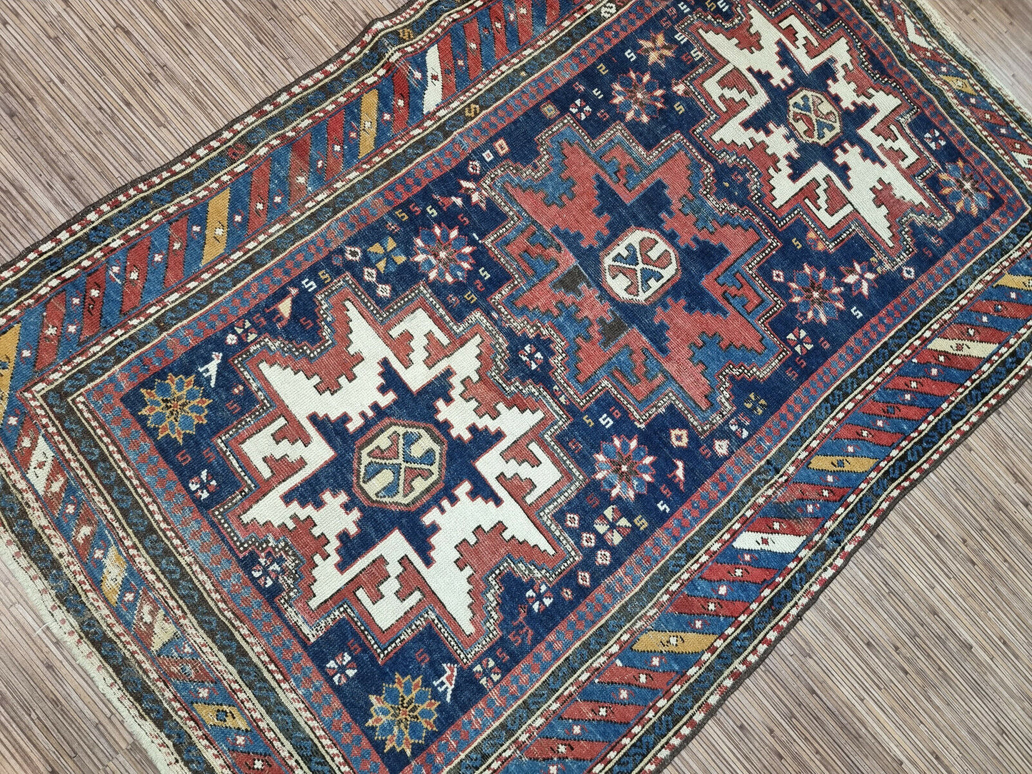 Symphony of Colors: Deep blues, radiant reds, earthy browns, and delicate cream accents create a mesmerizing visual harmony in this Antique Shirvan Rug.