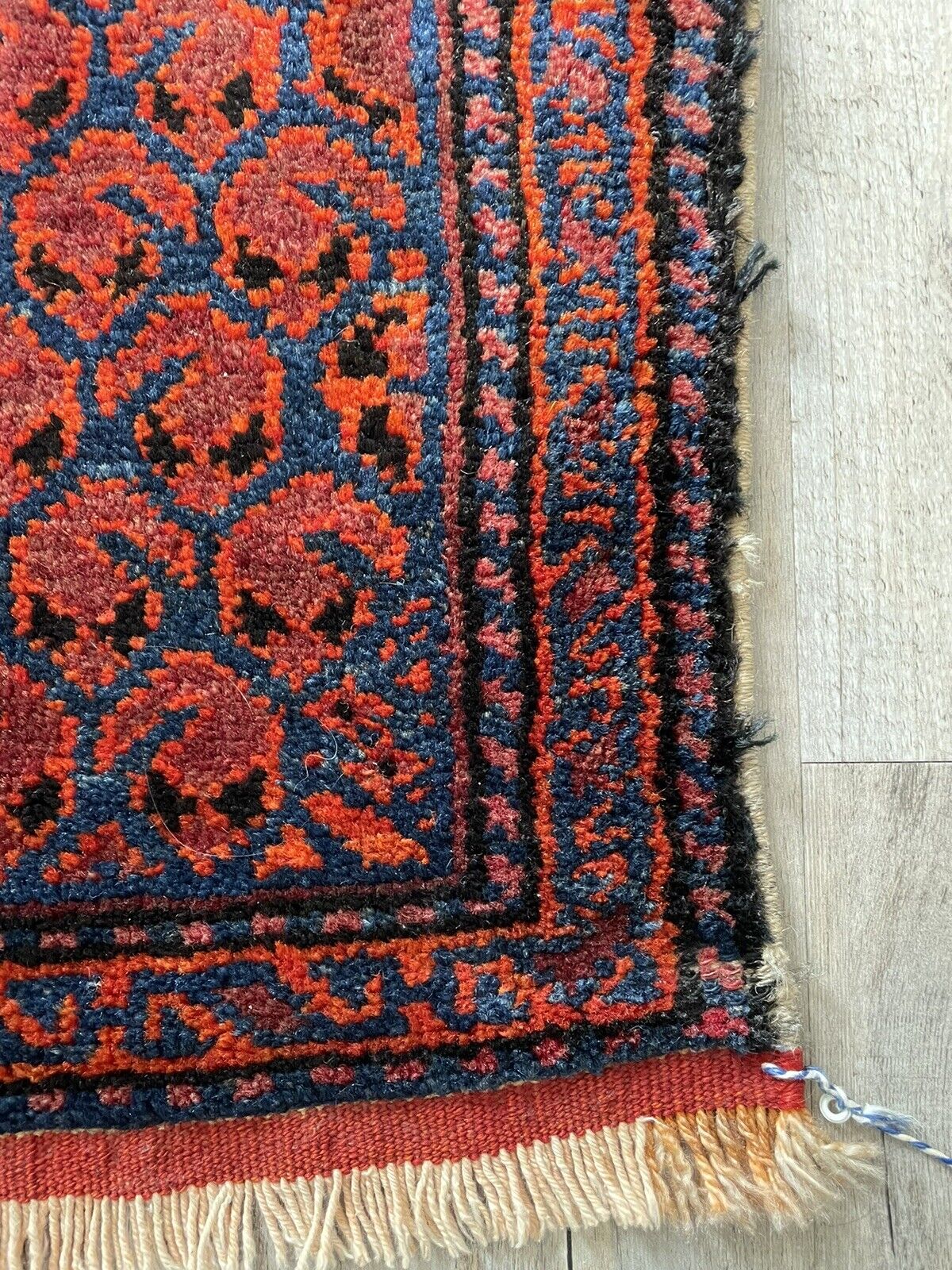 Hand-Knotted Construction: A close-up of the underside of the Shiraz bagface (1900s), revealing the hand-knotted construction and the natural color of the wool fibers.