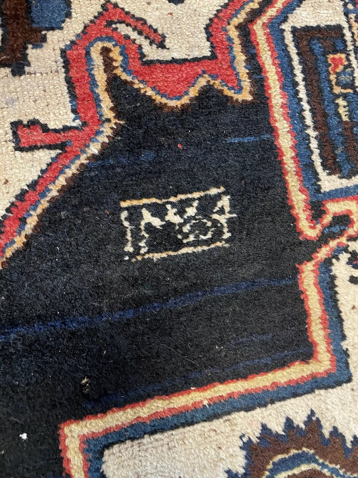 Deep red and blue antique rug with a decorative border
