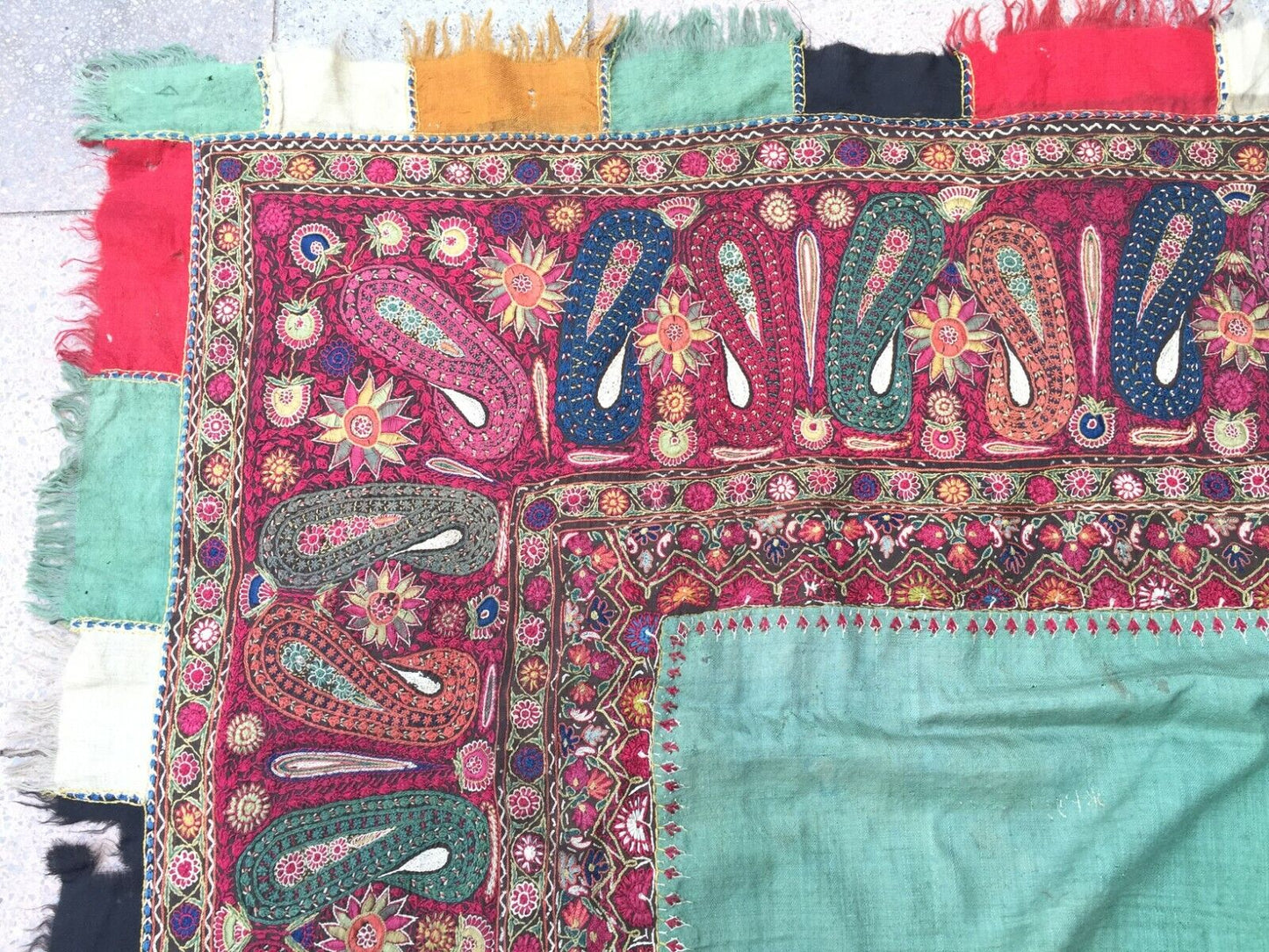 Artistic display of the shawl as a statement piece on a clothing rack, showcasing its rich green color and intricate motifs