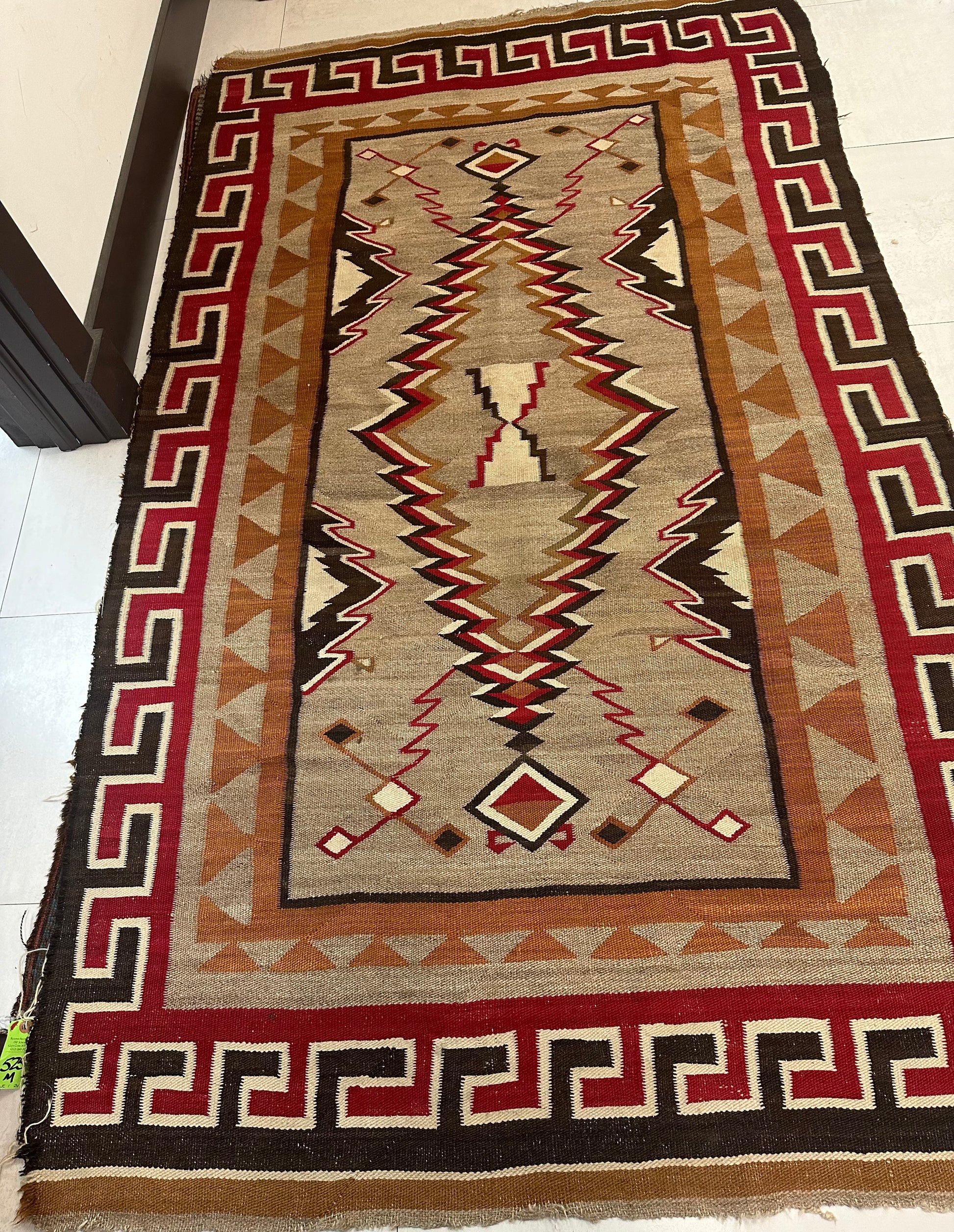 Close-up of bold red border with stepped key motifs on Navajo rug.
