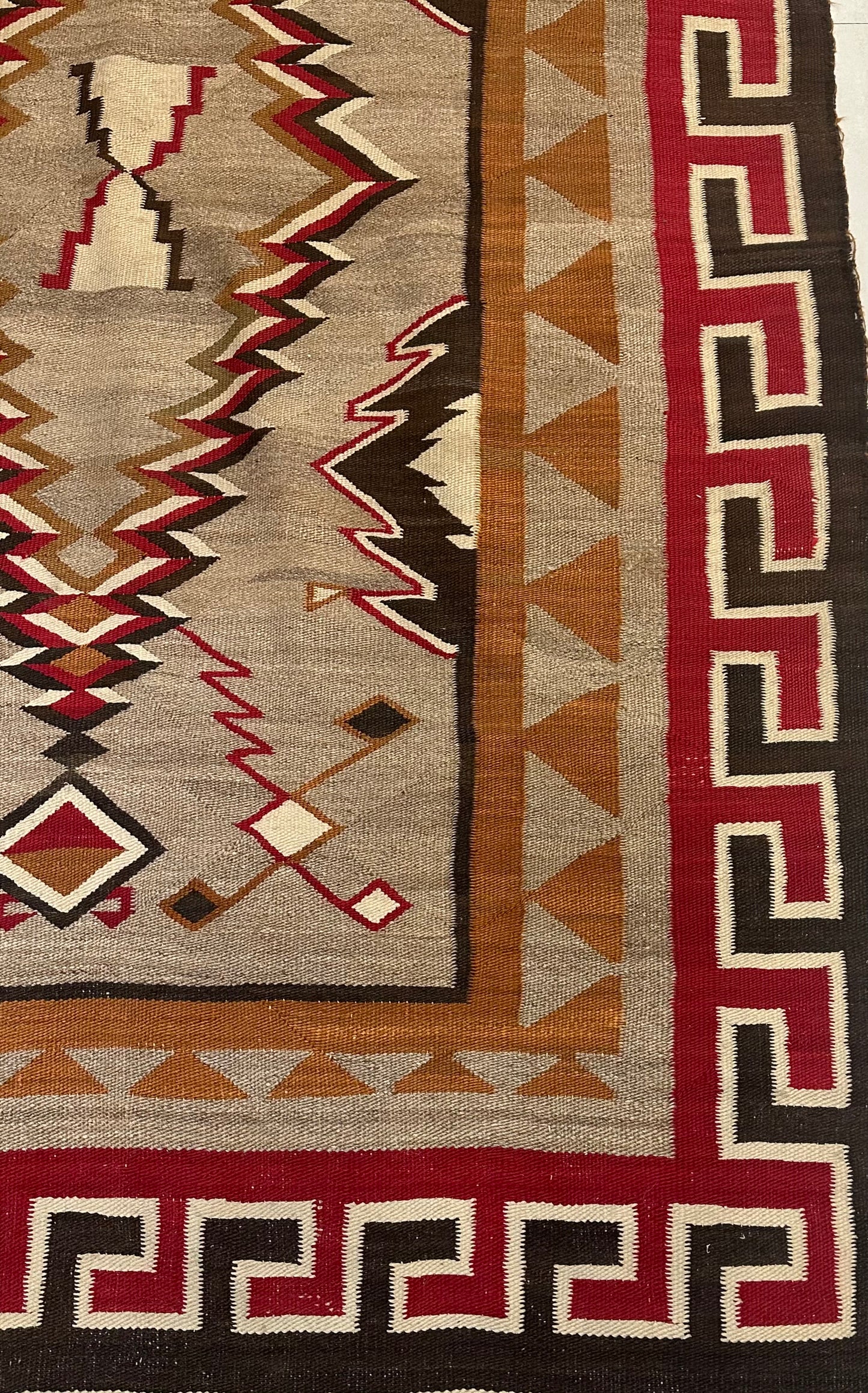 Vintage Native American Navajo rug with earthy brown, beige, and red tones.
