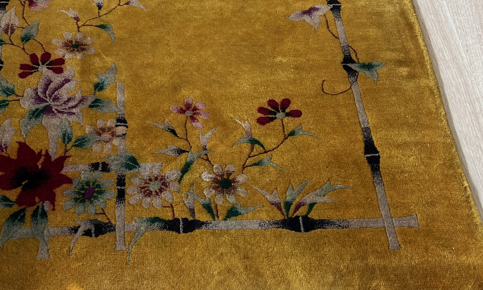 Detailed view of red, pink, and purple flowers on the vintage rug
