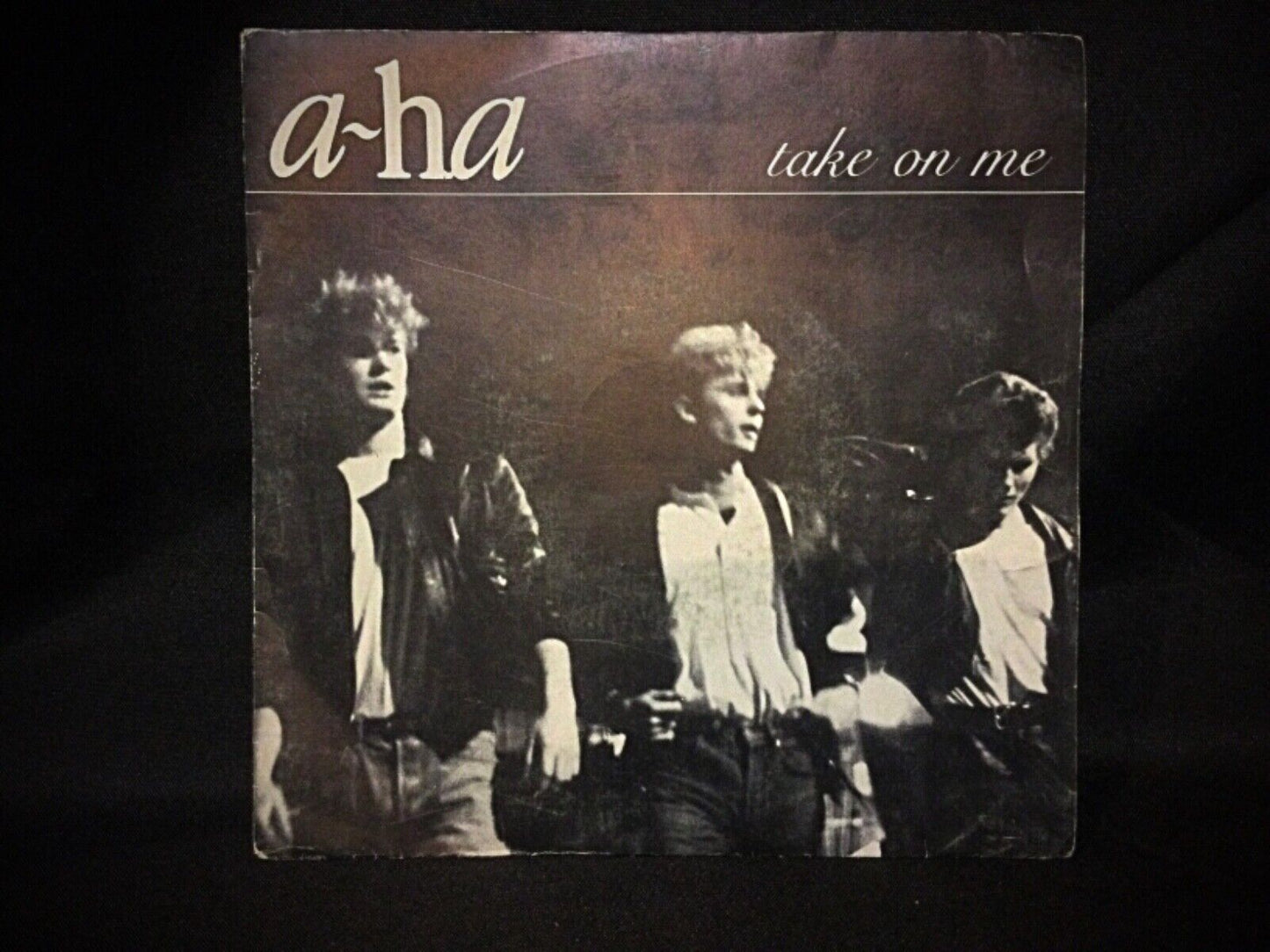 Close-up of the A-Ha "Take on Me" 45 RPM vinyl showcasing visible wear and scratches on the record.