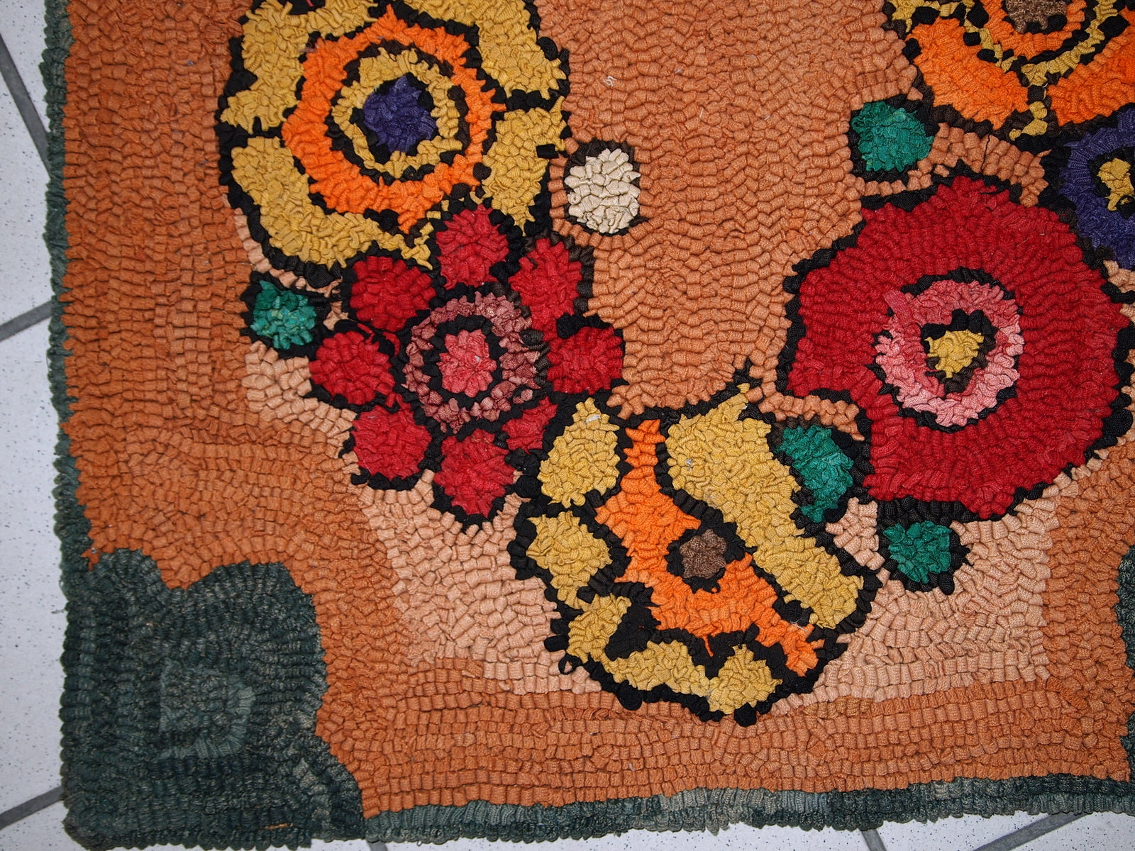 Vintage rug corner detail showcasing green flower design