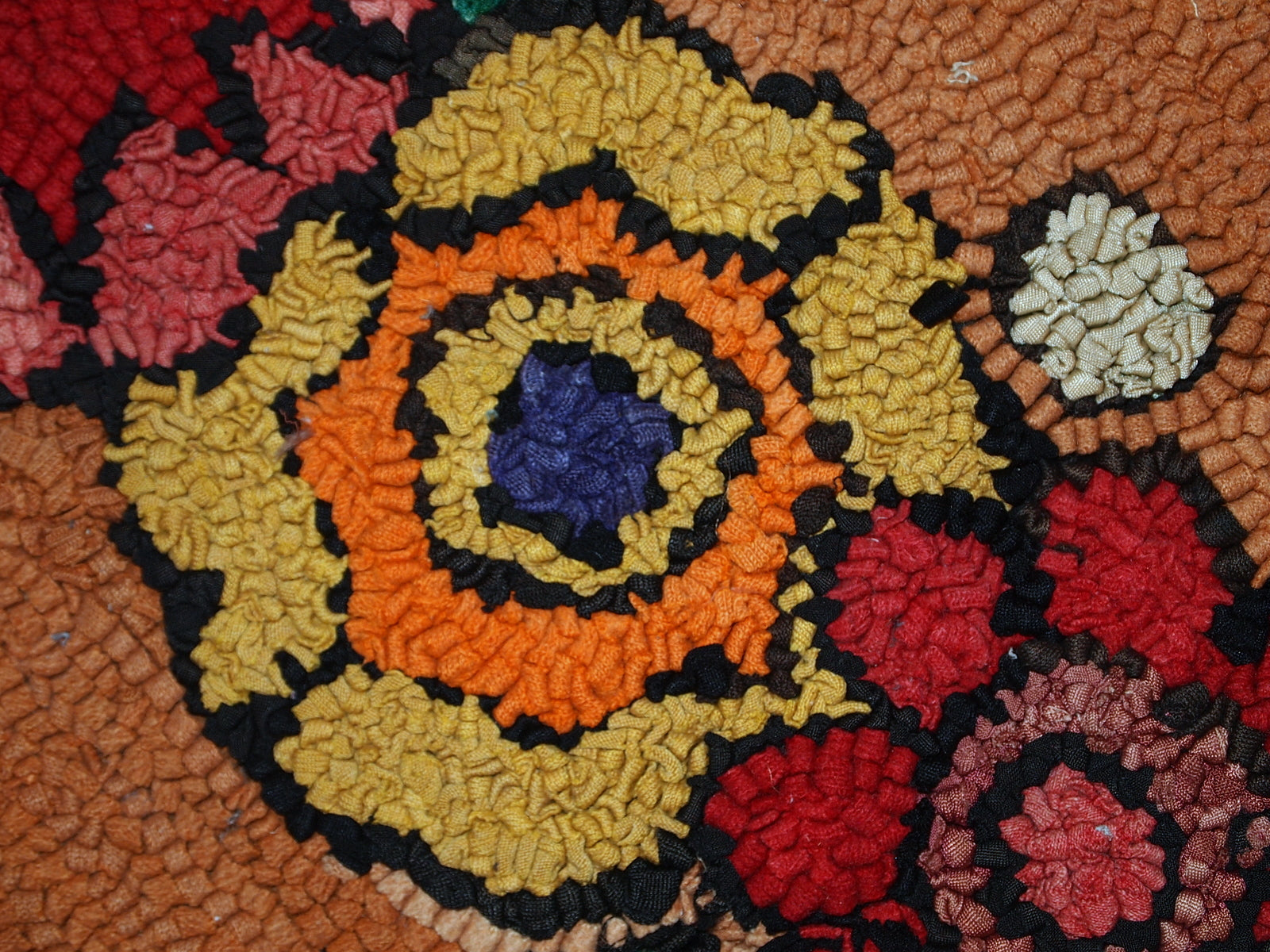 Detailed shot of the orange and green flower design on the handmade rug