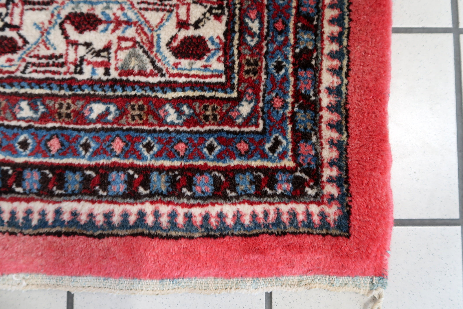 Handmade vintage Indian Seraband rug in original condition, it is unequally faded (one side is brighter then another) . The rug has been made in traditional pattern, it is from end of 20th century. The shades of the rug are mostly in pink and white. All-over design with repeating pattern. All dyes on this rug are natural. This is the type of rug woven in India to compete in the same market as rugs from Persia.