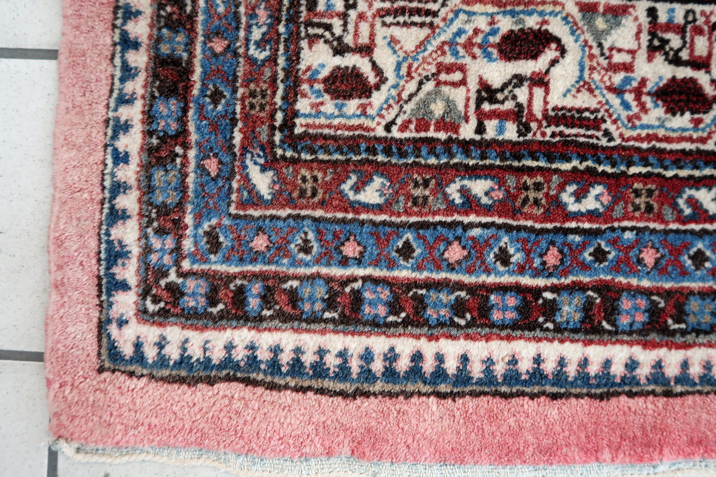 Handmade vintage Indian Seraband rug in original condition, it is unequally faded (one side is brighter then another) . The rug has been made in traditional pattern, it is from end of 20th century. The shades of the rug are mostly in pink and white. All-over design with repeating pattern. All dyes on this rug are natural. This is the type of rug woven in India to compete in the same market as rugs from Persia.