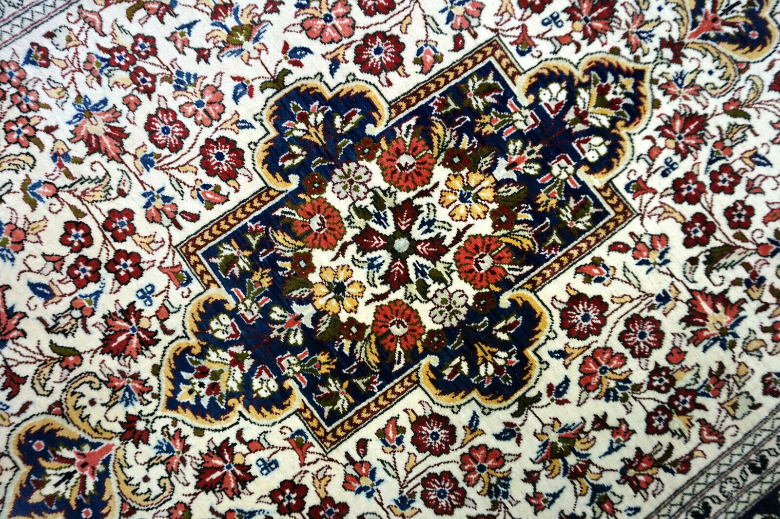 Handmade vintage Persian Qum rug in very busy floral design with natural colors. The rug has been made in silk. It is is from the end of 20th century in original good condition.